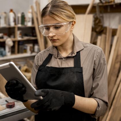 职业女木匠戴着护目镜拿着平板职业职业平板电脑