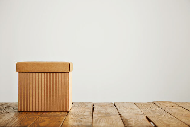 发送正面拍摄一个未贴标签的方形米色纸板箱与木地板上的白色隔离盖订单物体回收