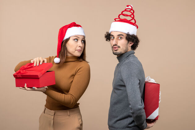 新的新年气氛和派对理念的俯瞰图-穿着圣诞老人帽手持礼物的惊喜可爱情侣圣诞老人上衣心情