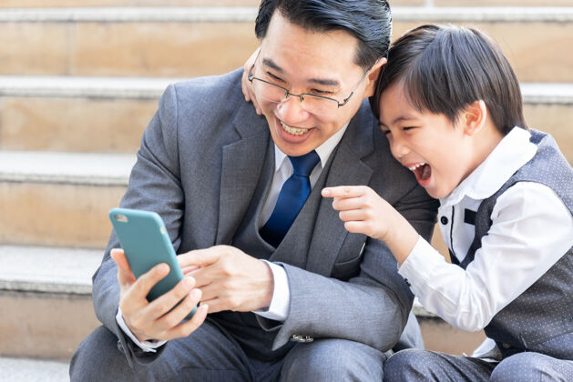 夫妇父子俩在市区商业区一起玩智能手机电话现代儿童