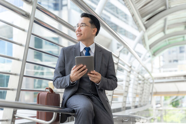 高级肖像亚洲商务人士商务区 高级有远见的行政领导与商业有远见的手机电脑在手-生活方式的商务人士的概念高管成功城市