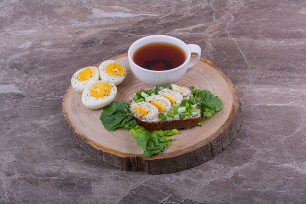 饮料烤面包配煮熟的鸡蛋和香草 再配上一杯茶饮料生物膳食
