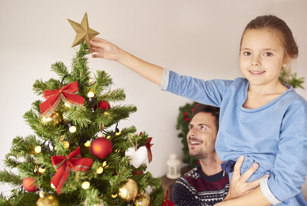 球体女孩和她爸爸在装饰圣诞树微笑装饰圣诞礼物