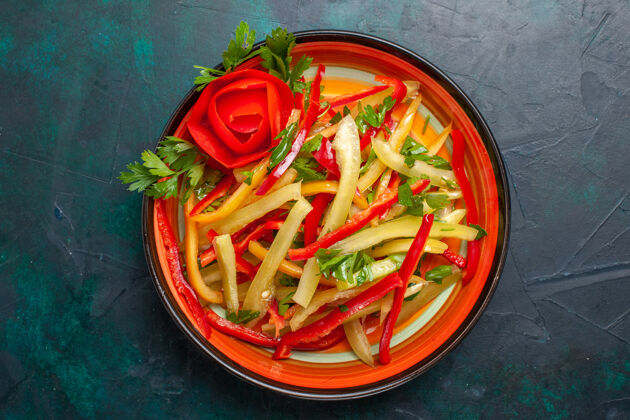晚餐顶视图切碎的甜椒不同颜色的蔬菜沙拉在深蓝色背景的盘子里健康盘子铃铛