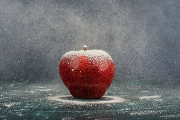 天然在蓝色背景上用粉末装饰的红苹果完整的苹果有机
