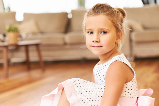 快乐室内拍摄的可爱的小公主穿着漂亮的粉红色裙子坐在家里的地板上准备孩子们在幼儿园的表现与可爱的蓝眼睛可爱孩子舞蹈