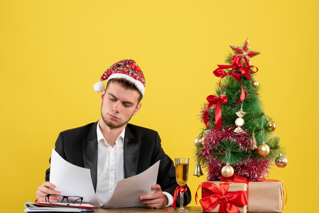 男性正面图：坐在工作场所后面的男工人正在检查黄色的文件圣诞节工作工作