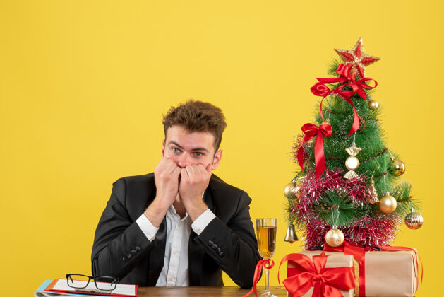 工作正面图坐在工作场所后面的男工人被黄色吓坏了男工人商人圣诞节
