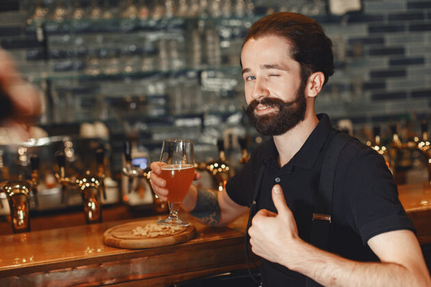 酒吧一个留着胡子的男人站在吧台旁 喝着酒杯里的酒领带酒吧帅哥