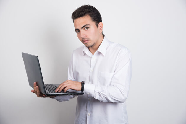 严肃庄重的商人使用白色背景的笔记本电脑年轻人表情办公室