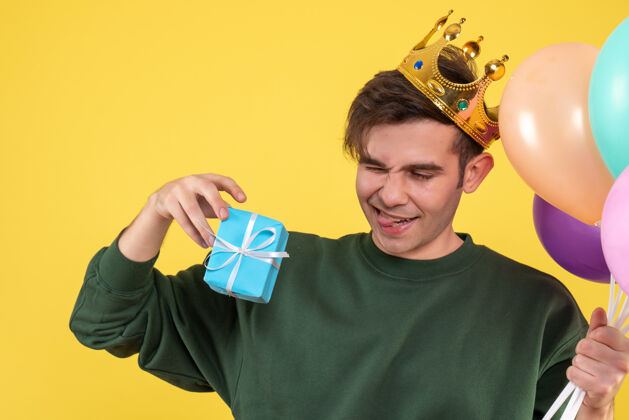 衣服正面图帅气的年轻人戴着皇冠拿着气球和黄色的礼物人礼物成人