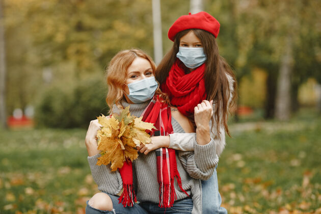 面具秋天公园里的一家人冠状病毒主题母亲带女儿安全秋天防护