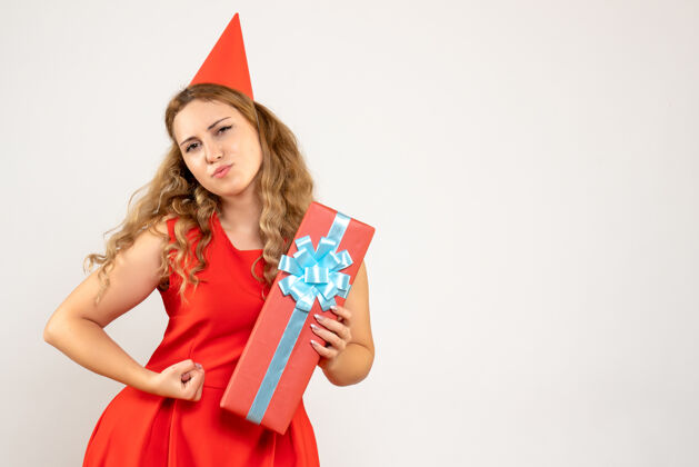 举行正面图身着红色连衣裙的年轻女性用礼物庆祝圣诞节年轻美丽情感