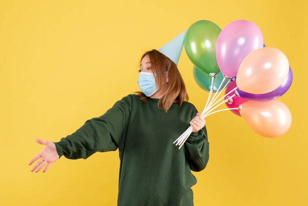 气球正面图：手持彩色气球的年轻女性年轻女性病毒气球