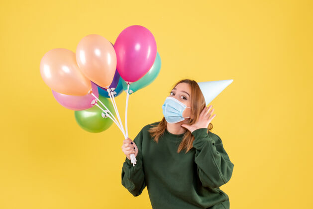 庆祝正面图：手持彩色气球的年轻女性生日Covid氧气