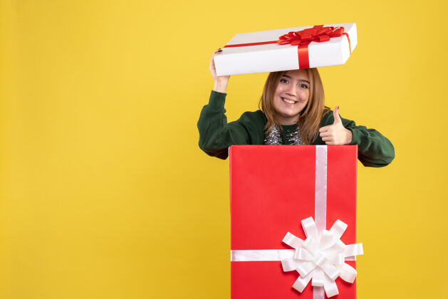 持有正面图年轻女性藏在礼物盒里礼物圣诞节里面