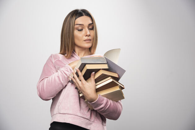 工人一个穿着粉色衬衫的女孩手里拿着一堆书 打开上面的一本读着女性服装人类