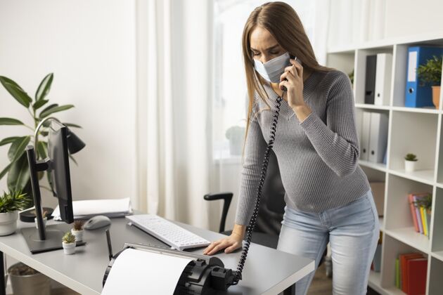职业带着医用口罩的孕妇在办公室接电话母亲工作职业