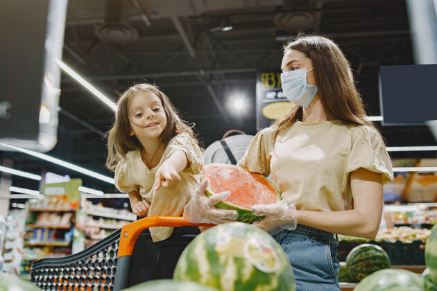 购物狂一家人在超市戴着防护面具的女人人们选择蔬菜母亲带着女儿冠状病毒食物买家Covid