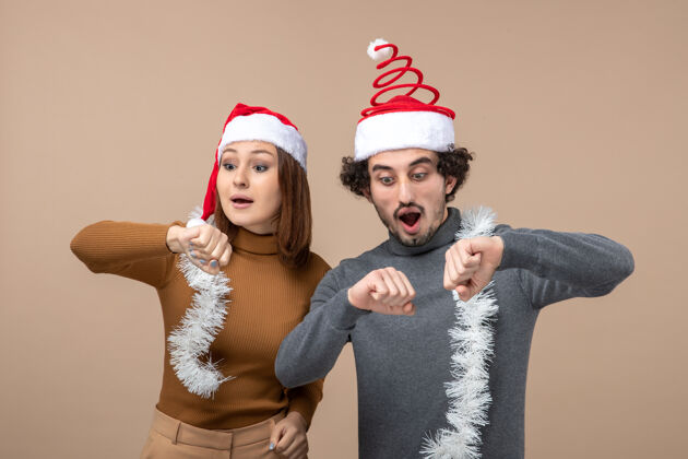 圣诞老人新年气氛喜庆的概念与兴奋酷满意可爱的夫妇戴着红色圣诞老人帽子检查他们的灰色时间兴奋帽子心情