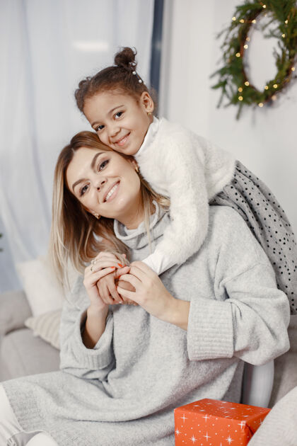 小人们在为圣诞节做准备母亲在和女儿玩耍一家人在节日的房间里休息孩子穿着毛衣花环装饰面纱