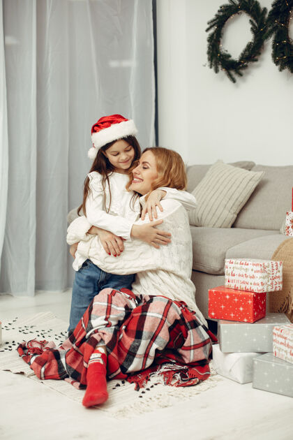 装饰人们在为圣诞节做准备母亲在和女儿玩耍一家人在节日的房间里休息孩子穿着红色毛衣圣诞节人赠送