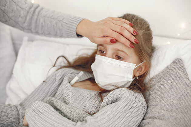 保健儿童中有冠状病毒母亲带着女儿孩子躺在床上戴着医用口罩的妇女冠状病毒圣诞节卧室