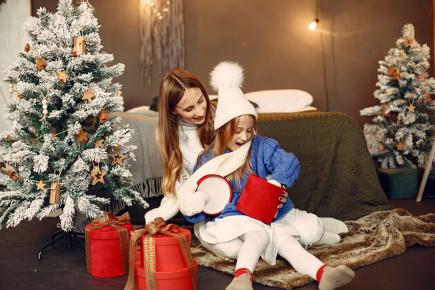 装饰人们在为圣诞节做准备母亲在和女儿玩耍一家人在节日的房间里休息孩子穿着蓝色毛衣快乐给毛衣