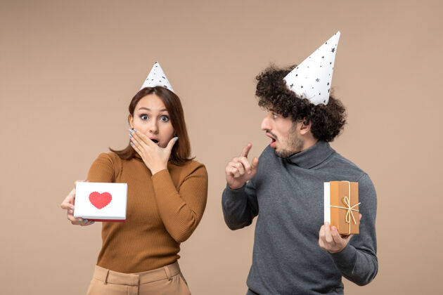 拍摄新年拍摄带着感情疯狂震惊年轻情侣戴新年帽的女孩带着心新的情侣年轻夫妇