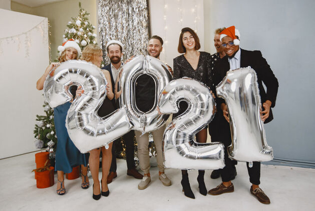 蓝色穿圣诞老人装潢的人穿黑色西装的人集体庆祝新年2021年拿着气球的人新年套装