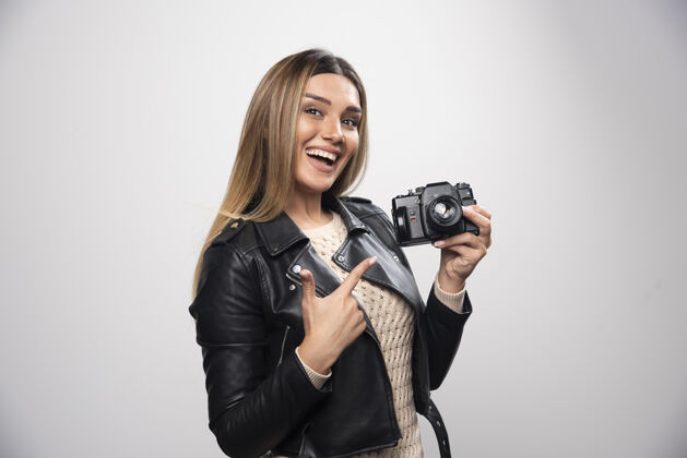聪明一位身穿黑色皮夹克的年轻女士 以积极微笑的态度 用相机拍照年轻人摄影姿势