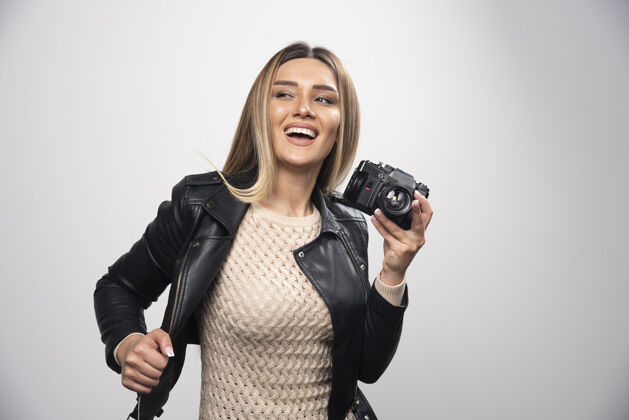 休闲一位身穿黑色皮夹克的年轻女士 以积极微笑的态度 用相机拍照快乐人姿势