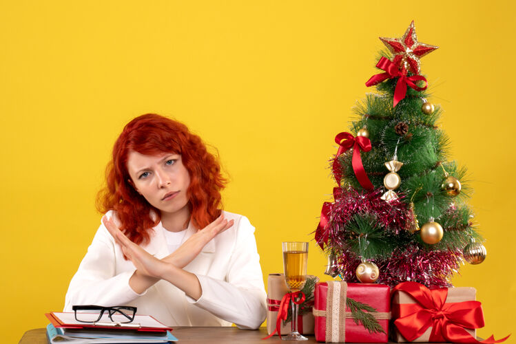 坐着女工人坐在桌子后面 手里拿着圣诞礼物和黄色的圣诞树桌子办公室圣诞