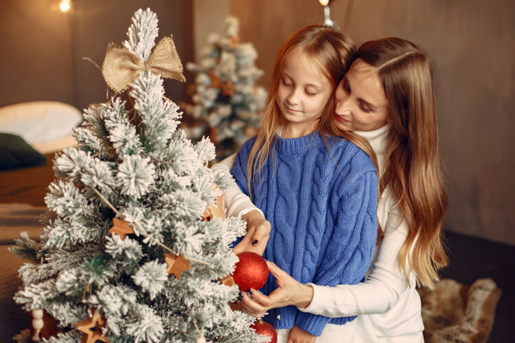 玩具人们在为圣诞节做准备母亲在和女儿玩耍一家人在节日的房间里休息孩子穿着蓝色毛衣人花环孩子