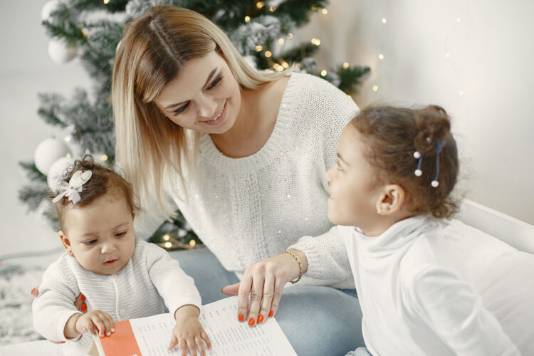 小人们在为圣诞节做准备母亲在和女儿们玩耍一家人在节日的房间里休息孩子穿着毛衣十二月传统花环