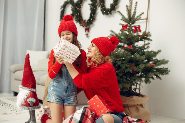 女儿人们在为圣诞节做准备母亲在和女儿玩耍一家人在节日的房间里休息孩子穿着红色毛衣装饰人肖像