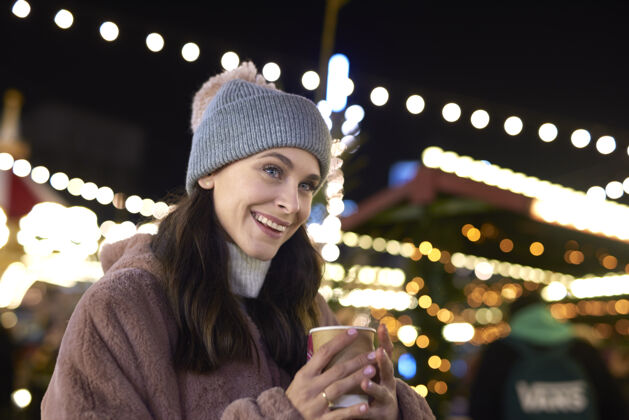 圣诞集市在寒冷的夜晚喝着熟酒的女人的特写镜头街道朋友女士专用