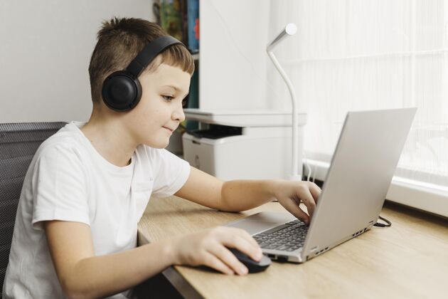 现代男孩用笔记本电脑和耳机回家室内电子科技