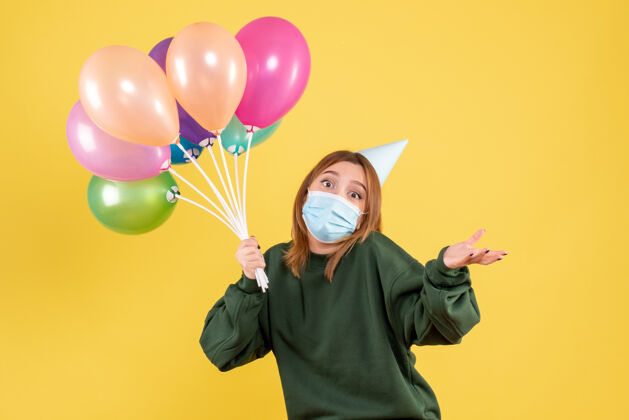 节日正面图：手持彩色气球的年轻女性病毒气球年轻女性