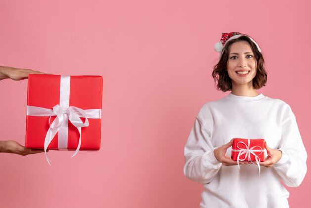 年轻女性年轻女子拿着小礼物 在粉色墙上接受男人的礼物接受男性女人