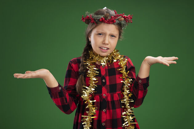 侧面小女孩戴着圣诞花环 穿着格子裙 脖子上挂着金属丝 双臂向两边张开绿色迷茫脖子