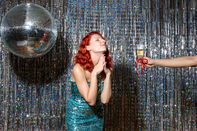 年年轻女性在派对上庆祝新年 在闪亮的窗帘上拿香槟乐趣采取庆祝