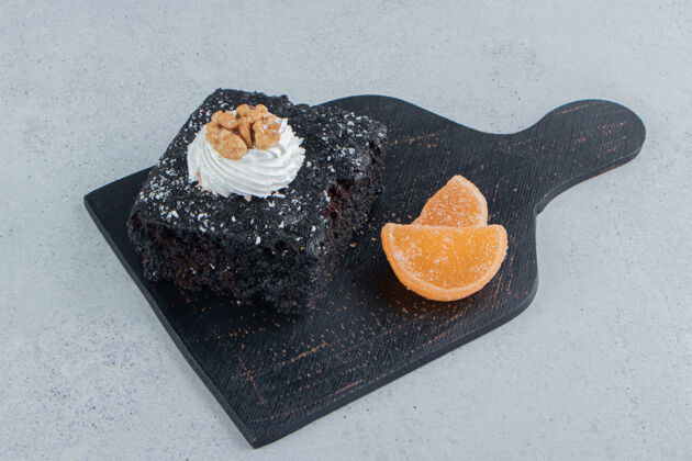糖巧克力蛋糕和果酱放在大理石背景的黑木板上烘焙奶油糕点