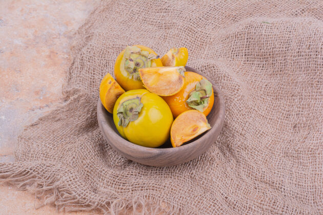 甜味黄枣李子放在粗麻布上的木杯里异国情调素食水果