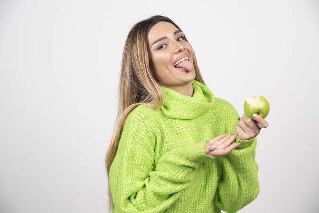 肖像穿着绿色t恤的年轻女子手里拿着一个苹果绿色苹果吃营养