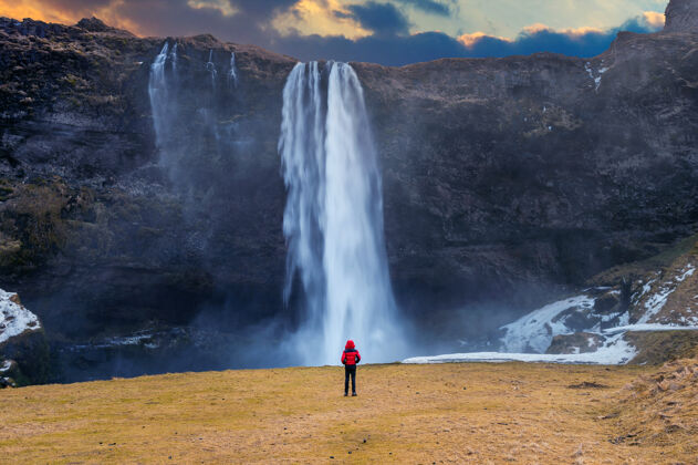 瀑布冰岛的塞尔加兰兹瀑布穿红色夹克的家伙看着塞尔加兰兹瀑布冬天目的地美丽