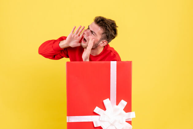 微笑正面图年轻男子站在礼物盒内呼叫里面圣诞节盒子