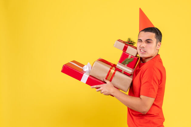 礼物盒黄色墙上年轻人拿着圣诞礼物的正面图人女士盒子