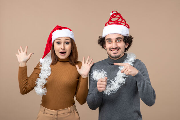 帽子新年心情喜庆的概念与兴奋酷满意可爱的情侣戴着灰色股票上的红色圣诞老人帽的形象可爱的情侣节日圣诞老人