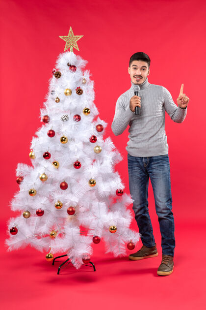 牛仔裤新年气氛积极的家伙穿着牛仔裤站在装饰圣诞树附近衣服心情圣诞树